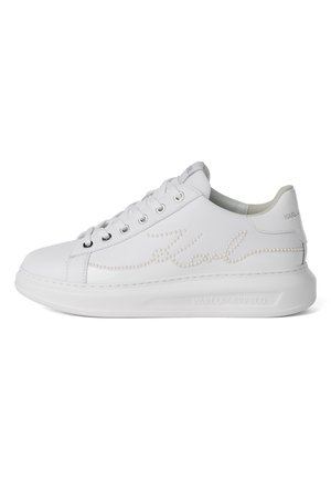 Zapatilla blanca de corte bajo con cierre de cordones y texto adornado con perlas en el lateral, con una suela gruesa en relieve con el nombre de la marca.
