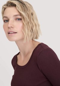Bourgondische top met lange mouwen en een ronde halslijn, van een zachte stof. De fitted design volgt prachtig de contouren van het lichaam.
