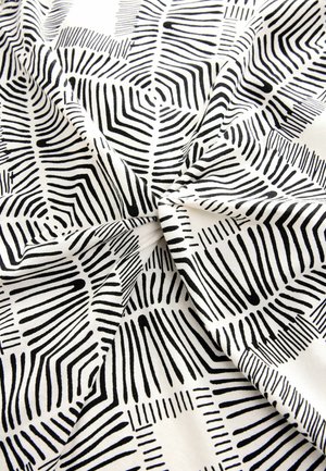 Crno-bijela tkanina s hrabrim, apstraktnim prugastim uzorkom različitih širina i tekstura, raspoređena u preklapajućem stilu.