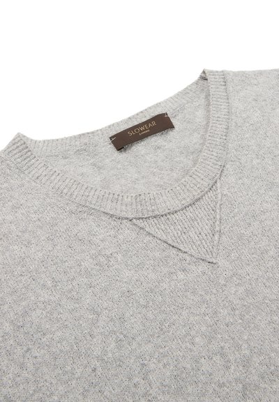 Suéter gris claro hecho de lana suave. Presenta un cuello redondo acanalado y una textura sutil, con un pequeño detalle triangular en el escote.