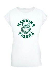 Balts T-krekls ar īsām sarullētām piedurknēm, uz kura attēlota zaļa tīģera sejas grafika un teksts "HAWKINS TIGERS" aplī.
