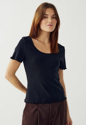 Top negro de punto de manga corta con escote redondeado, textura acanalada, dobladillo deshilachado y silueta ajustada. Combinado con pantalones marrones.