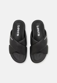 Svarta slidesandaler med ett korsande mönster, tillverkade av slät syntetmaterial, med vit "Levi's" logotyp på ovansidan.