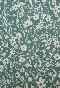 Blomstrete stoff med en teal bakgrunn som har hvite blomster og stilker, inkludert prestekrager og små klynger, som skaper et overordnet botanisk mønster.