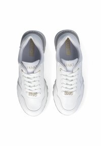 Zapatillas deportivas blancas con parte superior de cuero liso, presentan cierre con cordones, acentos dorados y una suela de goma texturada gris.