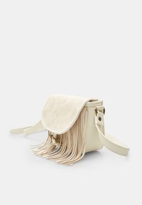 Sac à main blanc avec des accents à franges, présentant un rabat texturé, des accessoires en or et un corps lisse. Sangle ajustable incluse.