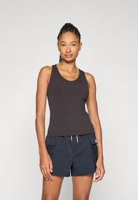 Sort tanktop med en rund halsudskæring, tætsiddende design, båret med marineblå shorts med mesh-lommer i siderne og snøre detaljer.