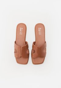Paire de sandales slides en cuir vegan marron avec larges brides découpées et bout carré sur fond blanc.