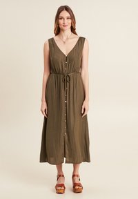 Olivgrünes Midikleid mit V-Ausschnitt und vorderem Knopfverschluss, tailliert und mit verstellbarem Bindegürtel. Glattes Material und ärmelloses Design.