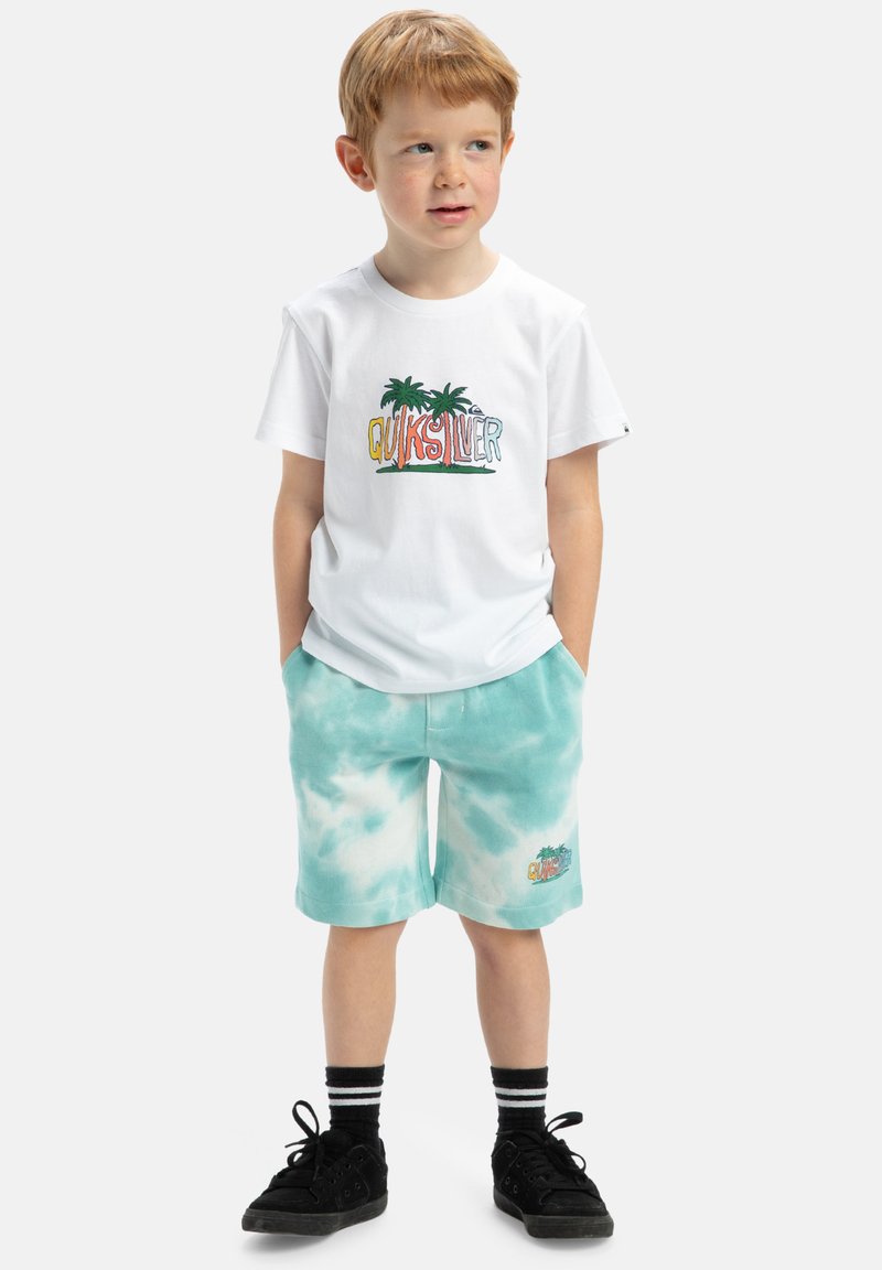 Biele tričko s farebným logom "Quiksilver", šortky v teal farbe s tie-dye vzorom a čierne topánky. Obsahuje grafiku mnohofarebných paliem.