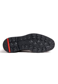 Black rubber shoe sole with deep treads, featuring a red stripe and a textured surface pattern for enhanced grip and durability.