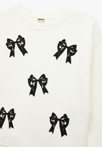 Hvid sweatshirt med flere sorte bueprint. Glat tekstur med rund halsudskæring og ribbede manchetter.