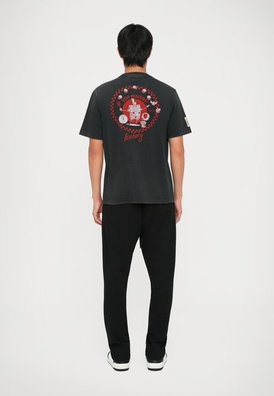 Czarny bawełniany t-shirt z graficznym nadrukiem na plecach z czerwonymi akcentami i napisem "Stay Positive" oraz "Iceberg." W połączeniu z czarnymi spodniami.