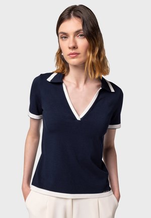 Navy polo shirt with white collar and sleeve trim, featuring a V-neck design and soft texture; suitable for casual wear.