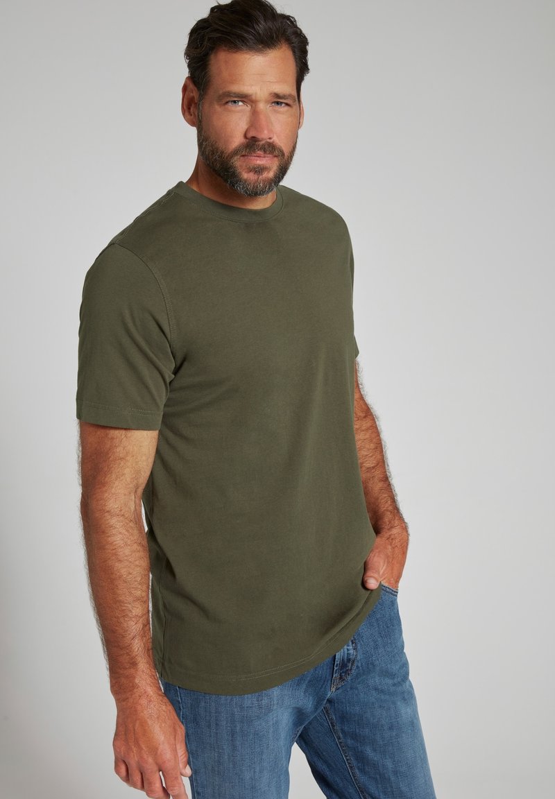 T-shirt in cotone verde oliva con maniche corte e colletto rotondo, abbinato a jeans in denim blu, esposto su uno sfondo neutro.