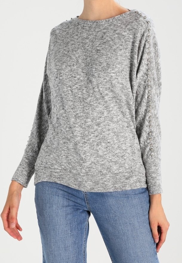 Harmaa neulepaita, jossa on pitkät hihat ja hopeiset niitit olkasaumoissa. Pehmeä kangas ja rento istuvuus.