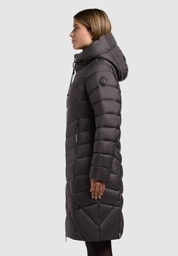 Tmavošedý, dlhý puffrový kabát s priliehavou kapucňou, vertikálnym prešívaním, bočnými zipsovými vreckami a logom na ľavom rukáve.