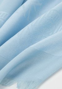 Sciarpa intrecciata di colore azzurro chiaro, con una texture liscia, motivi sottili e delicati bordi frangiati. Tessuto morbido e leggero che si drappeggia in modo elegante.