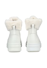 Witte hoge sneakers met een zachte, pluizige crème kraag, een soepele leren buitenkant en een dikke, stevige witte zool.