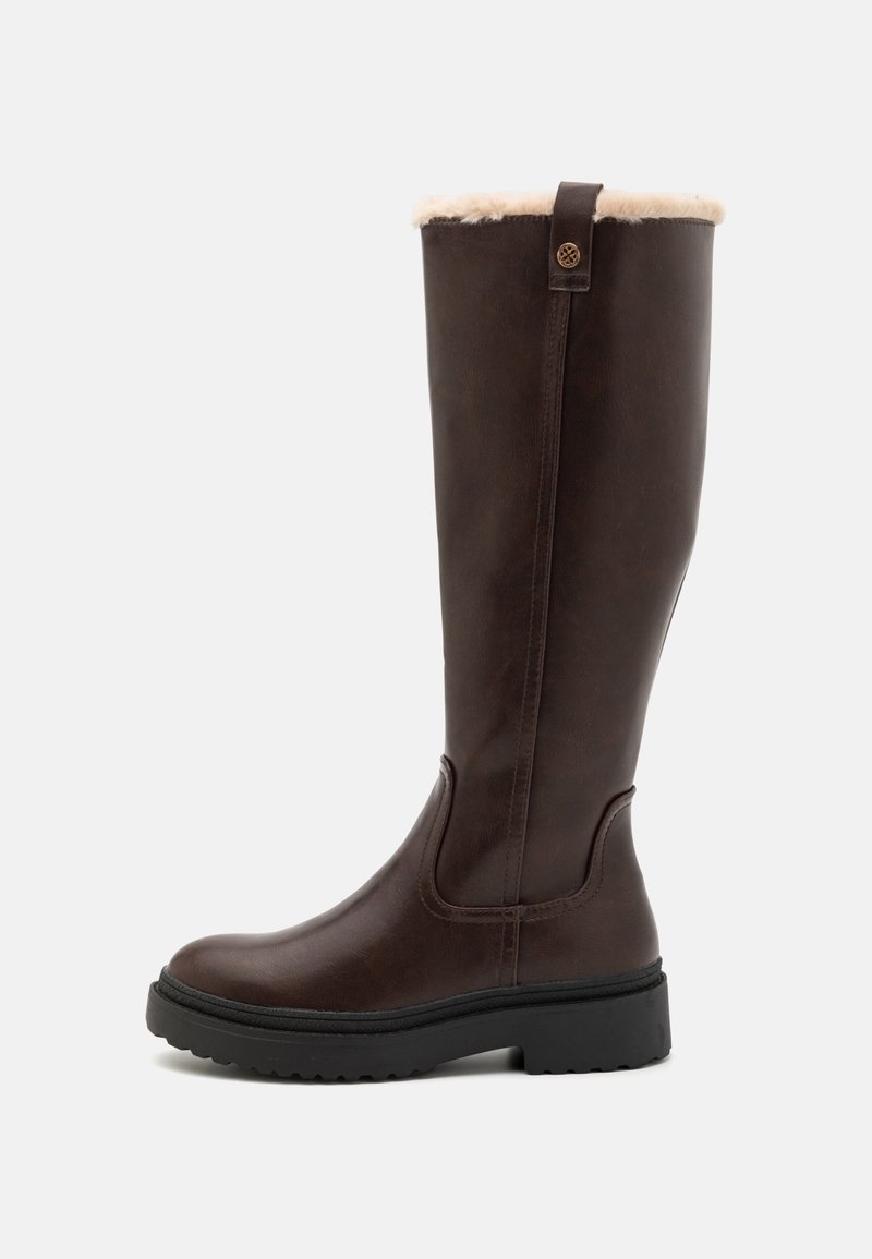 Botte haute en cuir brun foncé avec semelle noire épaisse et doublure en fourrure beige clair visible en haut.