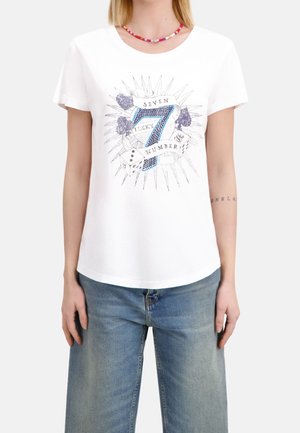 T-shirt en coton blanc présentant un graphisme bleu du chiffre « 7 » et le texte « SEVEN LUCKY NUMBER », entouré d'éléments décoratifs.