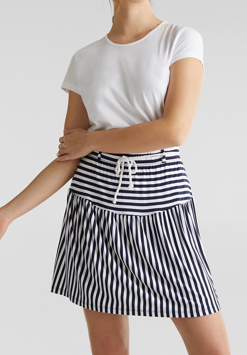 Jupe à rayures bleu marine et blanches avec une ceinture élastique et un cordon de serrage. Le design présente une silhouette évasée avec une texture froncée.
