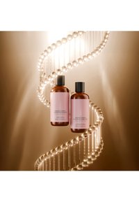 Zwei braune Flaschen mit pinkfarbenen Etiketten des Ceramid-Komplex Haarshampoos und Conditioners, schwebend vor einem leuchtenden Doppelhelix-Strang.