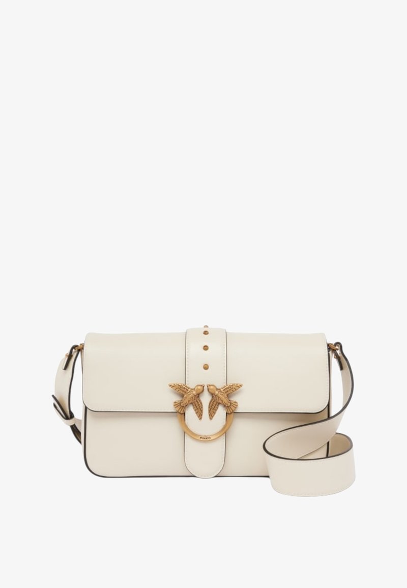Bolsa de mão em pele creme com fecho de aba, decoração de pássaro em tom dourado, três tachas decorativas e uma alça removível.