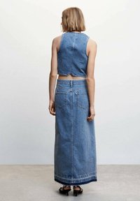 Conjunto de dos piezas de denim que incluye un top corto con un dobladillo en forma de ondas y una falda larga con el fondo deshilachado, ambos en azul claro.
