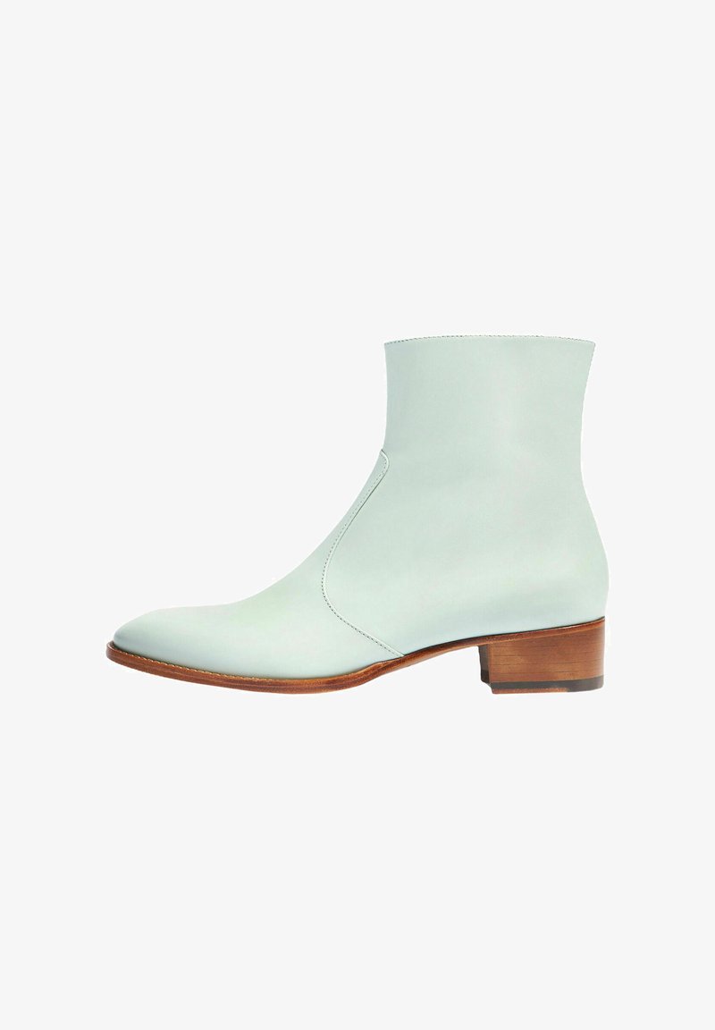 Botín de cuero verde menta con punta redonda, costuras mínimas y tacón bajo de madera. Textura suave y diseño elegante.