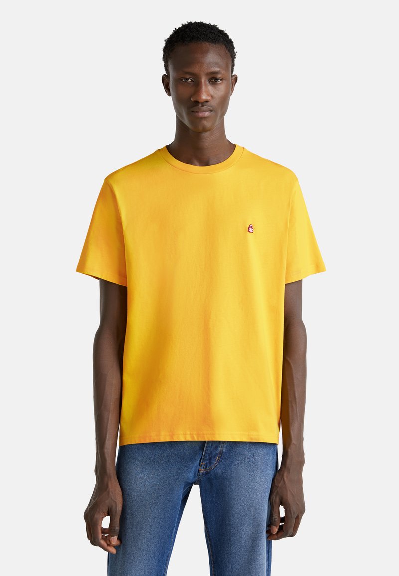 Felle gele katoenen t-shirt met een ronde hals en korte mouwen, voorzien van een klein logo geborduurd op de borst.