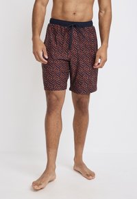 Mannen zwemshorts in rood en marineblauw met een chevronpatroon. Elastische tailleband met trekkoord, knielengte, gemaakt van lichtgewicht stof.