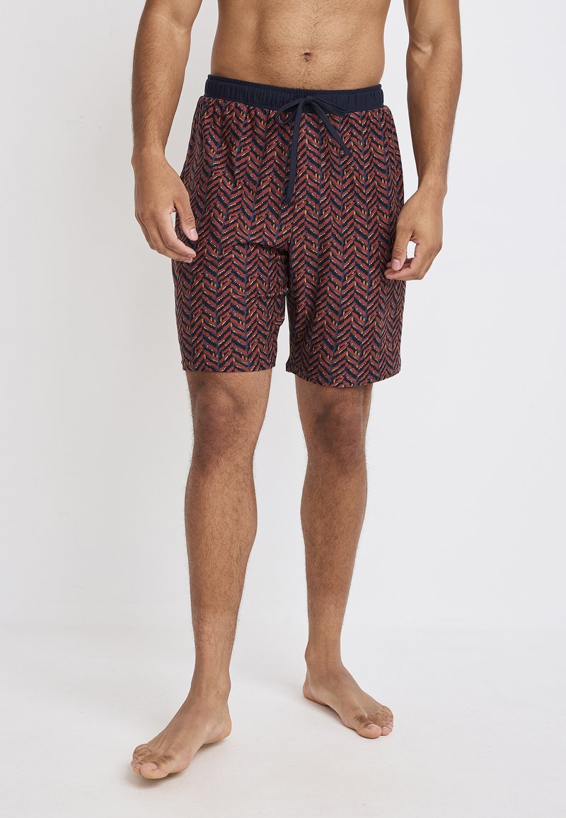 Mannen zwemshorts in rood en marineblauw met een chevronpatroon. Elastische tailleband met trekkoord, knielengte, gemaakt van lichtgewicht stof.