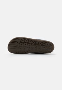 Schuhsohle aus Gummi mit runden Vorsprüngen für Traktion, gebogener Form und aufgedrucktem Markennamen "Camper" in Größe "38".