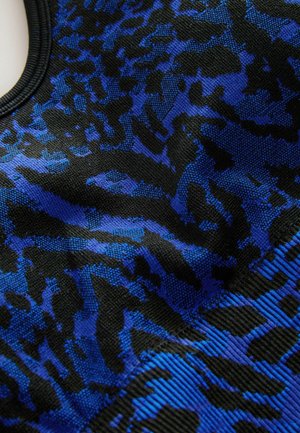 Texturerad tyg i nyanser av blått och svart med ett leopardmönster. Nærbilde visar vävningen och färgkontrasten.