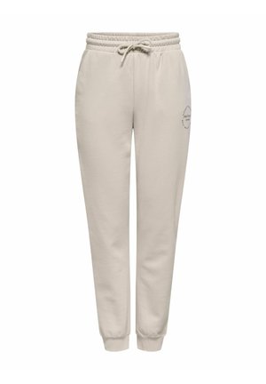 Pantaloni de trening bej cu șnur, manșete elastice și un mic logo circular pe partea superioară dreaptă a coapsei.
