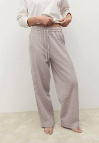 Pantaloni lounge leggeri e a righe in tessuto morbido. Presentano un elastico in vita con cordino e un design a gamba larga. Colore: beige e bianco.