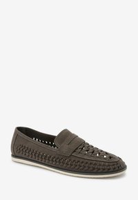 Brown suede slip-on shoe with woven detail and a smooth upper, featuring a prominent strap across the instep and a flat sole.
