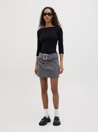 Black ribbed long-sleeve top, grey denim mini skirt with a wide belt and grommet details, black chunky loafers, white ankle socks.