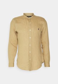 Beżowa lniana koszula z długim rękawem, kołnierzykiem stójką, zapięciem na guziki i małym granatowym haftowanym logo Polo na piersi.