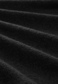 Close-up van zacht zwart stof met zichtbare textuur en parallelle plooien die zachte richels vormen.