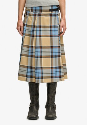 Beżowo-niebieska kratka na kilt o długości do kolan noszona z czarnymi butami do połowy łydki, przypięta czarnym paskiem z klamrą w talii.