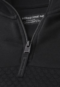 Giacca nera con zip caratterizzata da un motivo testurizzato, colletto a coste e un tirazip contrassegnato con "STREET ONE MEN" e il dettaglio "SEEK ADVENTURE".