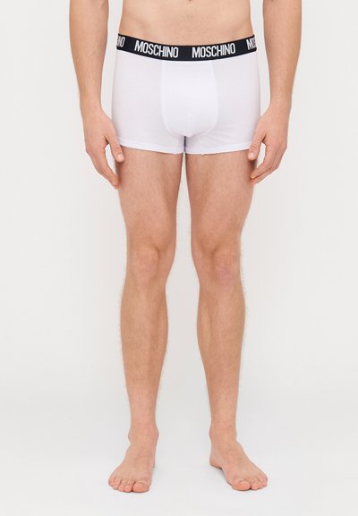 Biele boxerky s čiernym pásom s logom Moschino, vyrobené z hladkého a elastického materiálu, s priliehavým strihom a dĺžkou po stred stehien.