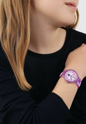 Child with light brown hair wearing a black sweater, showing a purple analog wristwatch with pink numbers on their wrist.