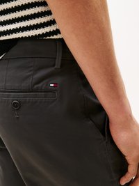 Graue Hose aus glattem Stoff, mit einer Gesäßtasche mit Knopf und einem kleinen Logo-Patch in Rot, Weiß und Blau.