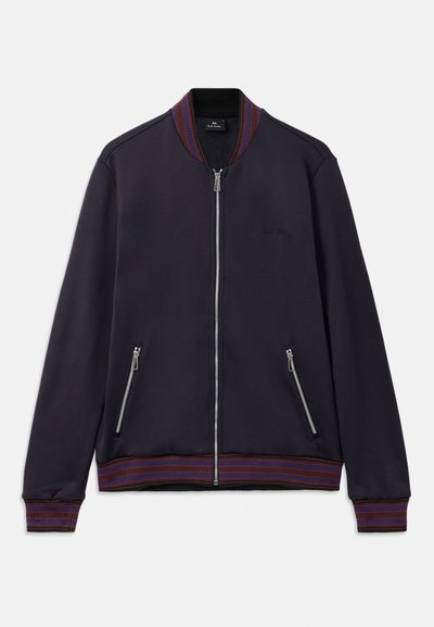 Tmavomodrý bomber s rebrovaným golierom s vínovými a fialovými pruhmi, so zipsom vpredu a postrannými vreckami, hladká textúra látky.