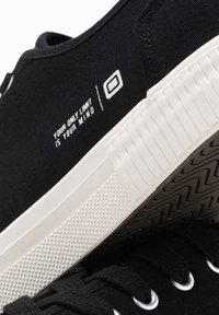 Sneaker in tela nera con suola in gomma bianca; le caratteristiche includono il testo bianco "IL TUO UNICO LIMITE È LA TUA MENTE" e dettagli testurizzati sulla suola.