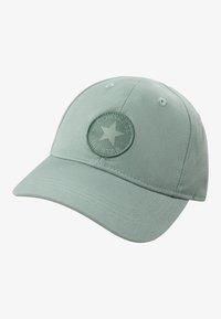Casquette en coton verte avec une couronne arrondie, ornée d'un logo circulaire brodé en relief et d'un détail cousu sur la visière.