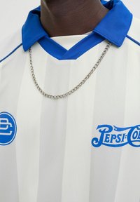 Bijela prugasta majica s plavim ovratnikom i detaljima, sa srebrnim lančićem i plavim Pepsi logotipom na prednjoj strani.